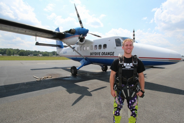 tandem student stands in front of skydiving plane