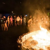 skydivers gather around bonfire at night