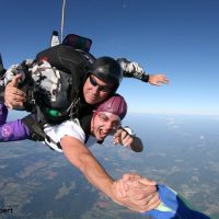 Skydive Orange tandem skydiver holding hand of videographer