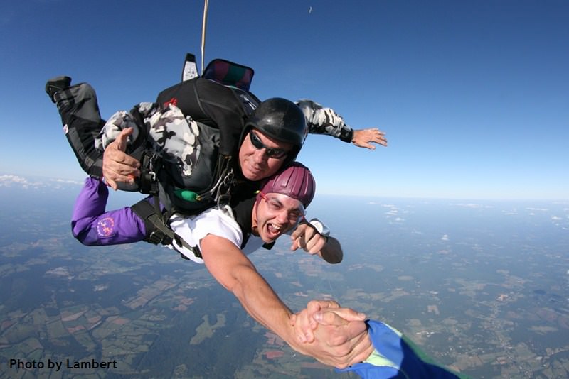 Skydive Orange tandem skydiver holding hand of videographer