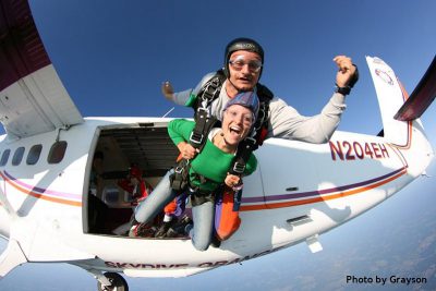 first time skydiver exiting plane with instructor