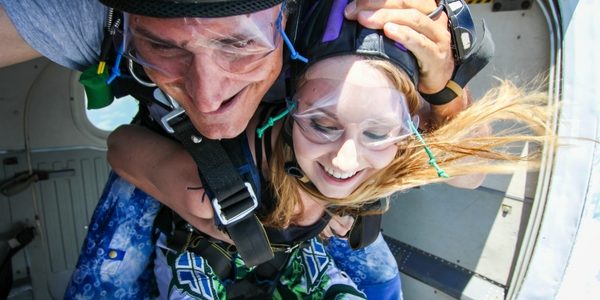 instructor makes sure tandem skydiving student is safe before exiting plane