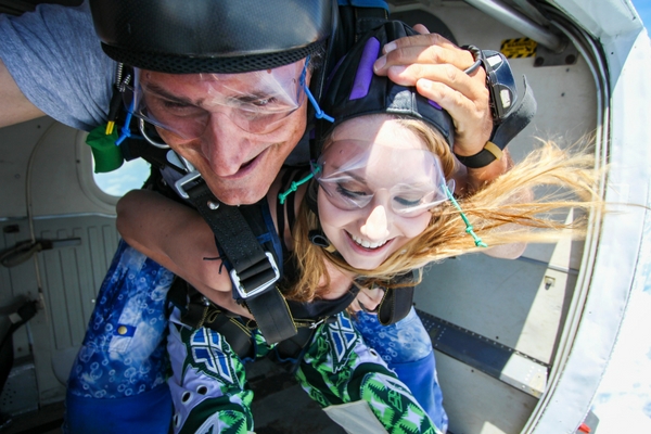 instructor makes sure tandem skydiving student is safe before exiting plane