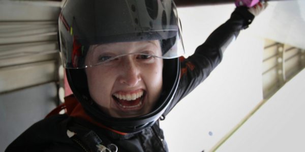 female skydiver gives a big smile before exiting plane